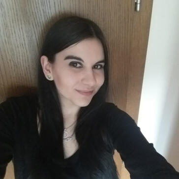 A picture of a woman with dark brown hair and dark brown eyes wearing a black shirt smiling into the camera.